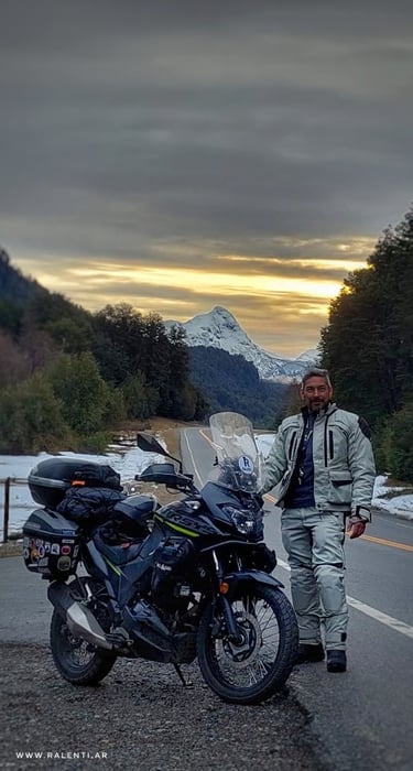 a man standing next to a motorcycle on a road